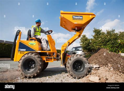 A builder driving a mini dumper truck on a house extension, building ...