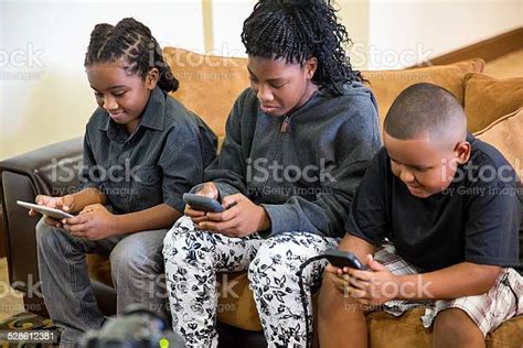 Three Black Children Playing Games On Their Electronic Devices Stock ...