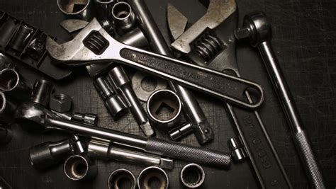 A GREASY MALE HAND DROPS SOME TOOLS ON A PILE OF AUTOMOTIVE WRENCHES AND SOCKETS. BEAUTIFUL ...