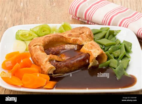 Classic British dinner of Toad in the Hole with vegetables and thick gravy - studio shot Stock ...