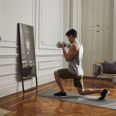 a man is doing exercises with dumbbells in front of a mirror and television