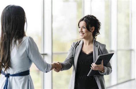 Two happy businesswomen shaking hands at the window stock photo