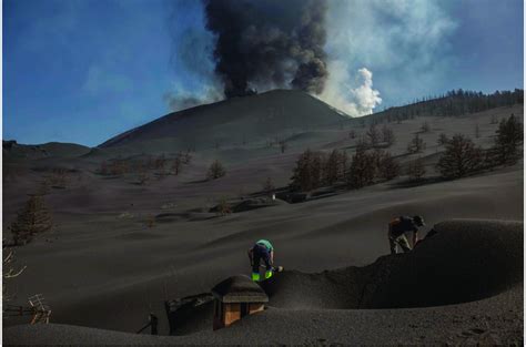 Workers use shovels to remove volcanic ash that has piled on top of a ...