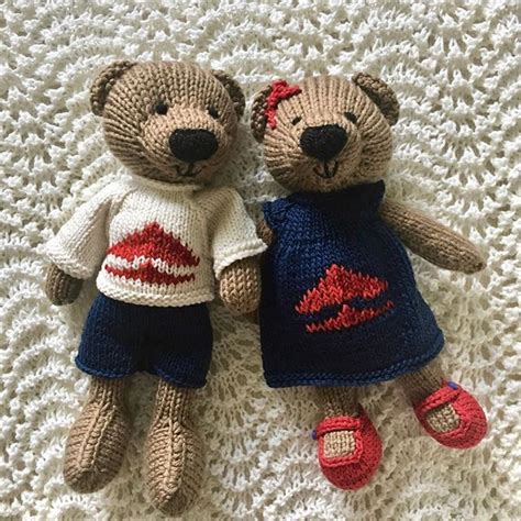 two knitted teddy bears laying next to each other on a white crocheted surface