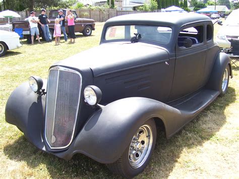 an old black car parked on top of a grass covered field