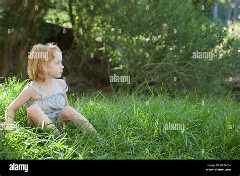 Little girl sitting in grass Stock Photo - Alamy