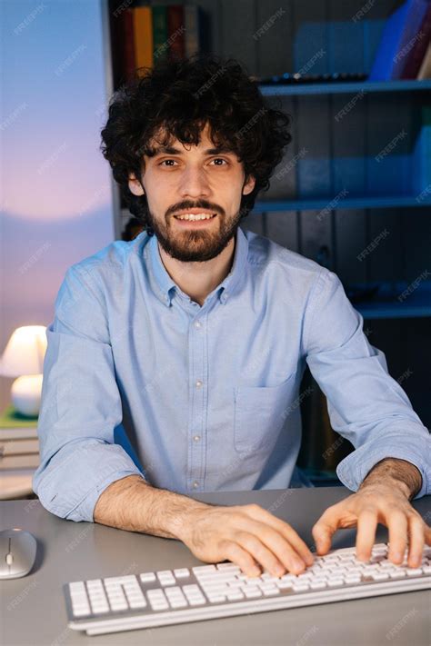 Premium Photo | Front view of smiling bearded young man looking at camera and typing online ...