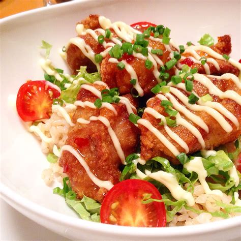 Japanese-style fried chicken on a bed of hot brown rice, garnished with tomatoes, spring onions ...