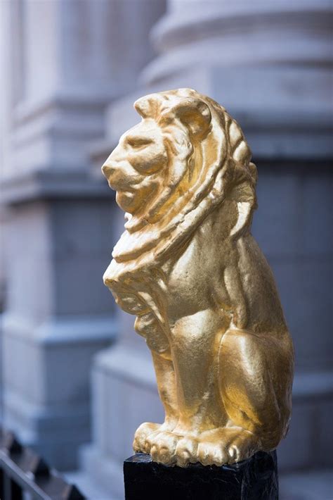 a golden lion statue sitting on top of a black block