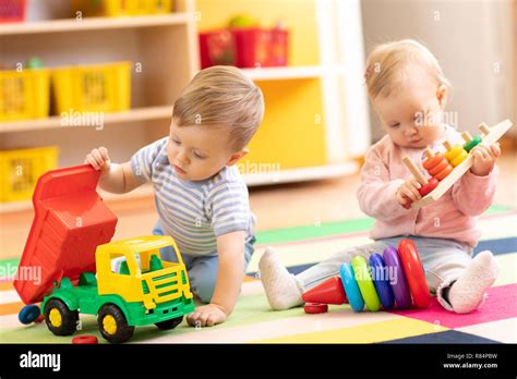 Kids playing with educational toys. Children sit on a rug in a play ...