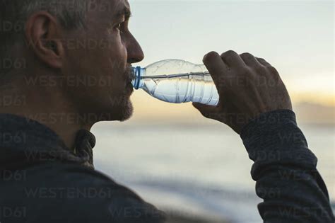 Close-up of man drinking water at beach stock photo