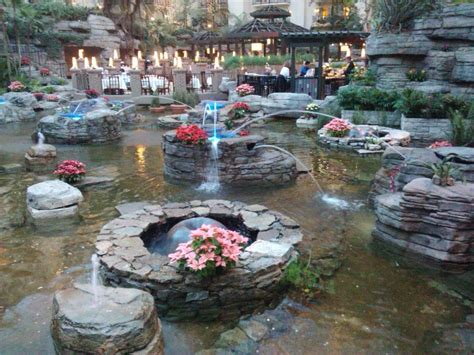 an outdoor fountain surrounded by rocks and flowers in the middle of a ...