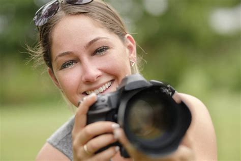 Close-up portrait of smiling woman using dslr camera outdoors ...