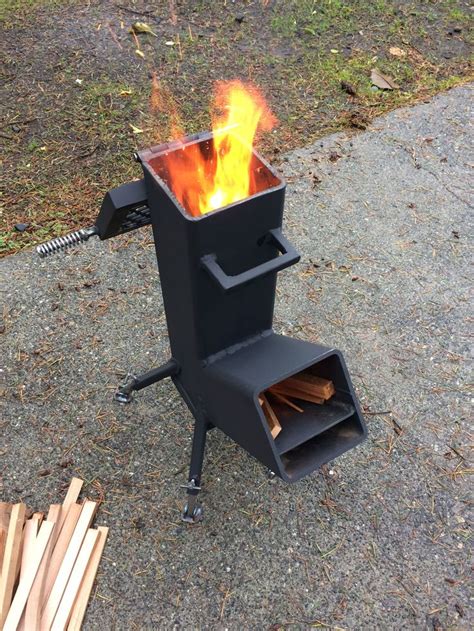 a fire pit sitting on top of a sidewalk next to some wooden sticks and logs