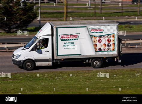 Krispy Kreme delivery van driving on the road. Doughnuts delivered fresh daily. Truck delivering ...