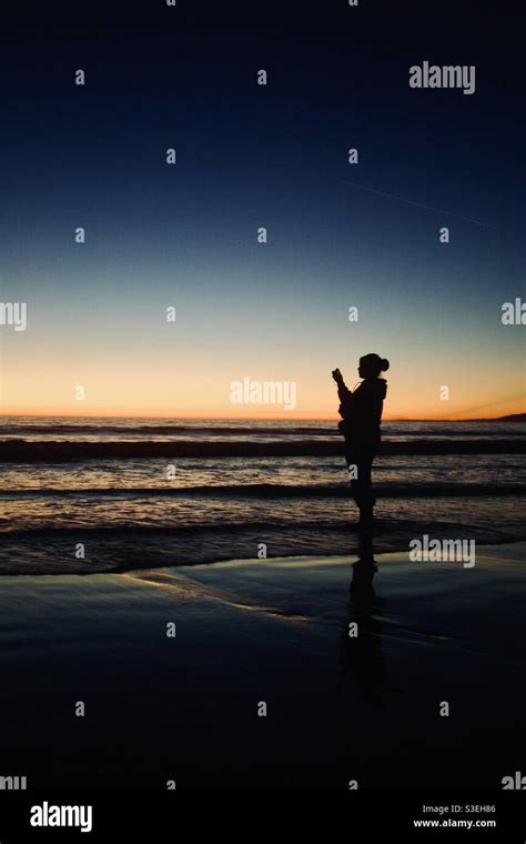 Young woman barefoot on a beach at sunset Stock Photo - Alamy