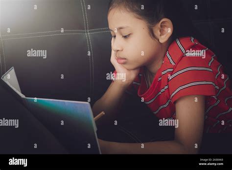 Little girl doing homework on sofa bed under light at home. education concept Stock Photo - Alamy