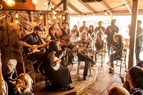 a group of people sitting around each other playing guitars and singing in front of an audience