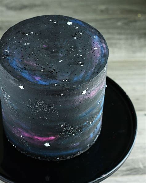 there is a black cake with purple and blue frosting on the top that has ...