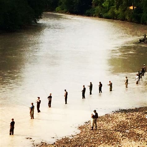 there are many people standing in the water and one is holding a fishing rod,