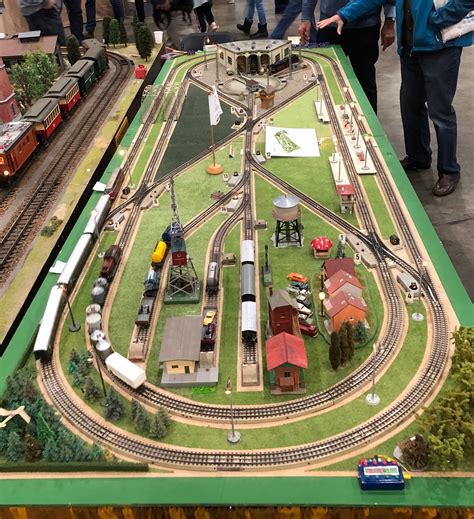 a model train set is displayed on a table with people looking at the ...