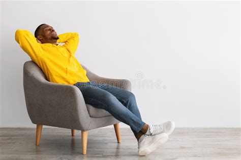 Black Guy Relaxing Sitting in Comfortable Chair Over Gray Wall Stock ...