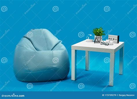 Bean Bag, White Coffee Table with Candles on it and in Glass Candlestick, Green Flower in Pot ...