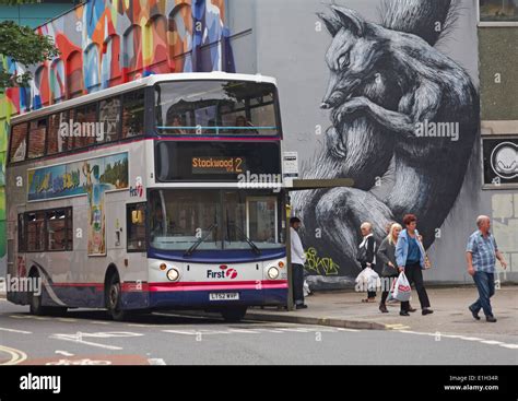 bus picking up passengers at bus stop by street art graffiti at Stock ...