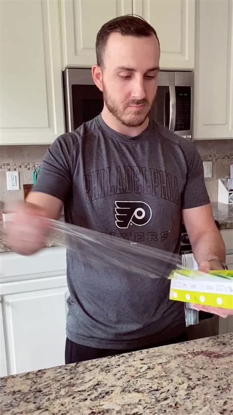 a man standing in front of a kitchen counter holding a pizza box with ...