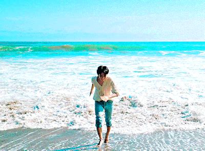 a woman is walking in the water at the beach