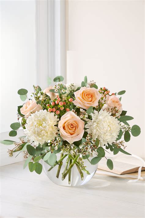 a vase filled with white and peach flowers