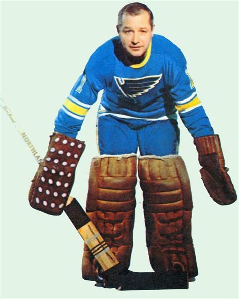 a man in blue and yellow uniform holding two hockey gloves on his feet ...