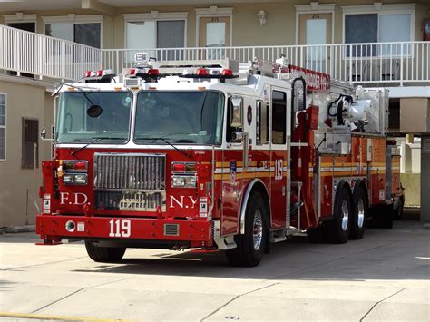 a red fire truck parked in front of a building with balconies on the ...