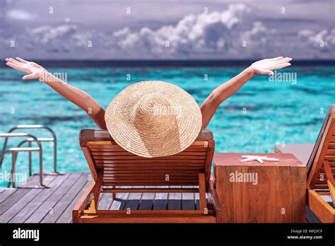 Luxury female tanning on the beach, wearing big stylish hat, enjoying beautiful seascape, summer ...