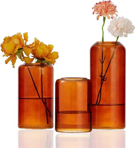 three orange vases with flowers in them