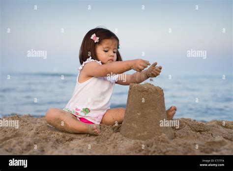 Young girl making a sand castle on the beach in the late evening Stock Photo - Alamy