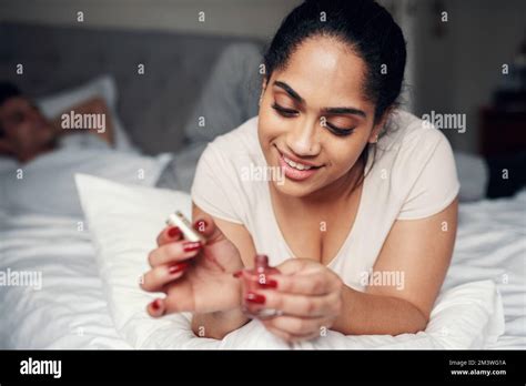 Dont underestimate the power of red nail polish. a beautiful young woman applying nail polish to ...