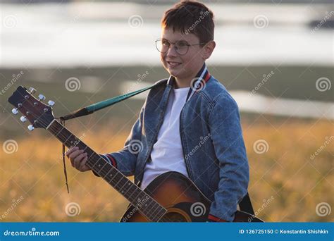 Young Teen Boy Playing on Acoustic Guitar at Summer Field on Sunset ...