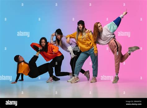 Group of dancers, boys and girls dancing hip-hop in stylish clothes on colorful gradient ...