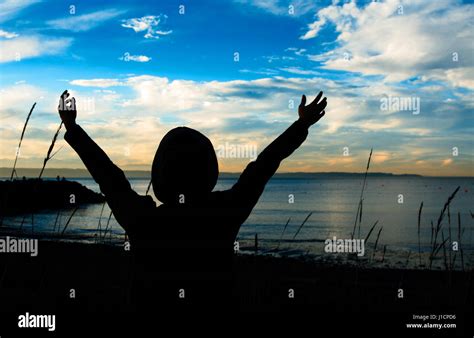 A praying woman in silhouette during the sunset Stock Photo - Alamy