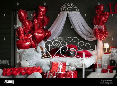 Valentines in the interior. Dark bedroom with a white bed decorated ...