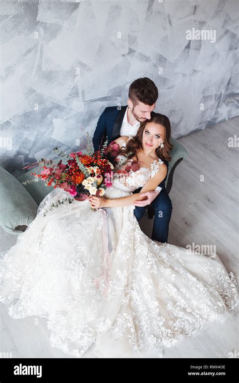 Wedding couple indoors is hugging each other. Beautiful model girl in white dress in studio. Man ...