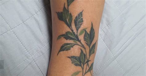 Leaves tattoo located on the ankle, watercolor style.