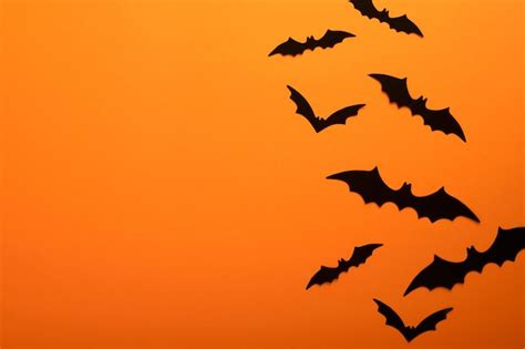 Premium Photo | Orange halloween background flock of black bats for halloween black paper bat ...