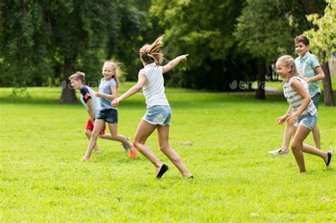 group of happy kids or friends playing outdoors Stock Photo by dolgachov