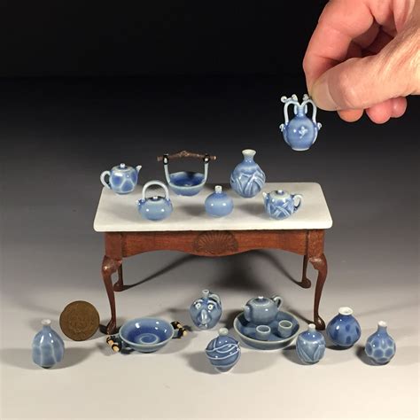 a hand is reaching for a miniature blue and white tea set on a small table