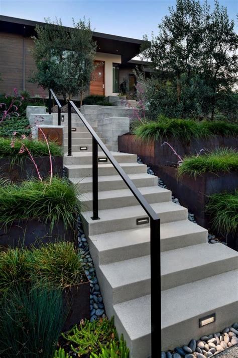 Polished concrete steps guide visitors towards the main entrance, with a metal railing along the ...