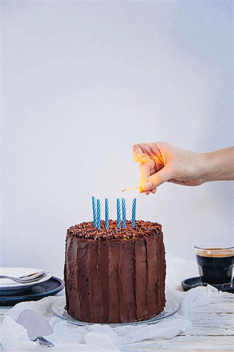 a person lighting candles on a chocolate cake