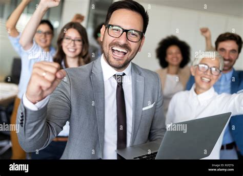 Happy business people celebrating success at company Stock Photo - Alamy