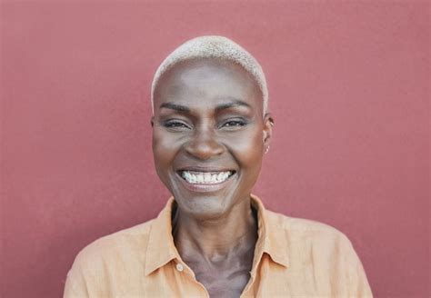 Cerca de la mujer mayor feliz sonriendo - persona negra de moda con pelo rubio corto | Foto Premium